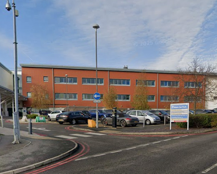 Hospital exterior with parked cars in main car park, related to doctor caught intimate with nurse mid-surgery incident.