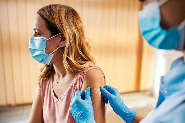 Healthcare professional wearing gloves applies a bandage to a woman's arm debunking common health myths.