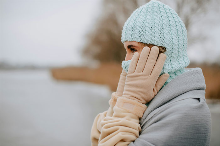Woman wearing winter clothes and gloves outdoors near water illustrating health myths exposed by doctors