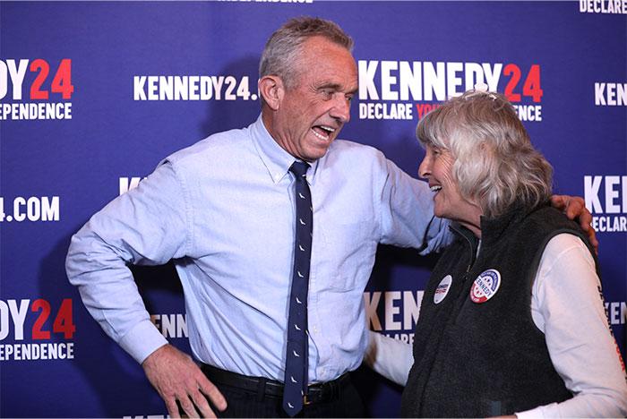 Two people smiling and talking at an event with a background featuring Kennedy24 health myths banner.