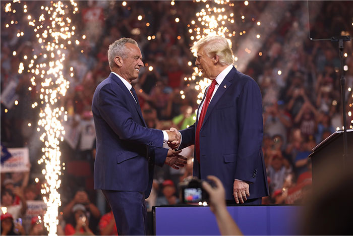 Two men in suits shaking hands on stage with sparks in the background, illustrating health myths debated by doctors.