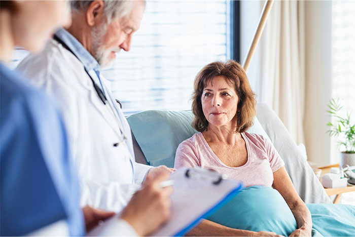 Patient in hospital bed talking to doctor and nurse during a medical checkup about faking illnesses being exposed