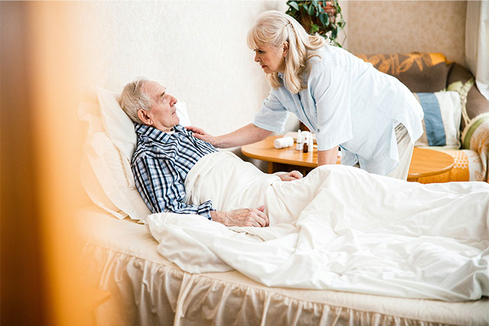 Elderly man in bed being cared for by nurse highlighting fake illnesses and exposure in healthcare settings.