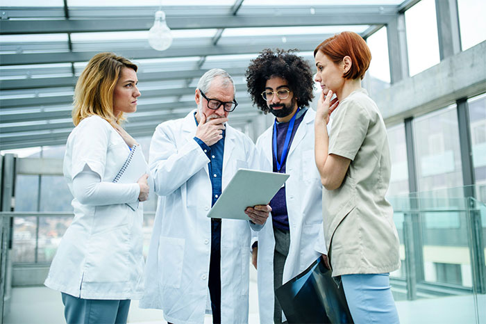 Group of doctors examining patient files discussing cases of people faking illnesses and getting instantly exposed.