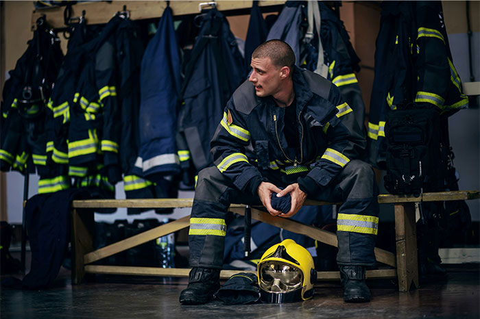 Firefighter sitting in uniform with helmet on the floor, related to people trying to fake illnesses and getting exposed.