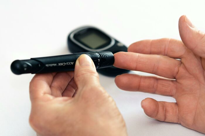 Person using diabetes test device to check blood sugar on fingertip, relating to patient lies and medical issues.