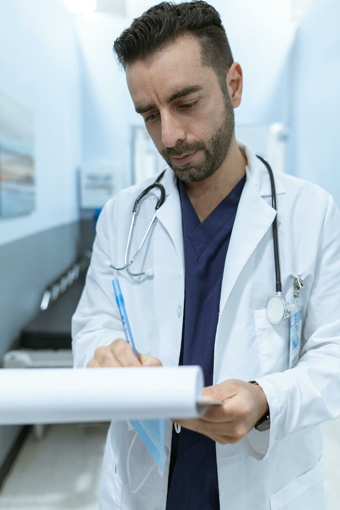 Male doctor in a white coat writing notes, examining records, illustrating patients trying to fool doctors with lies.