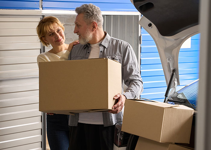 Couple packing boxes into a car, illustrating people who tried living double lives while moving or relocating.