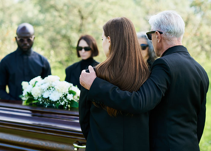 Mourning people at a funeral standing by a coffin, symbolizing secrets and the consequences of living double lives.