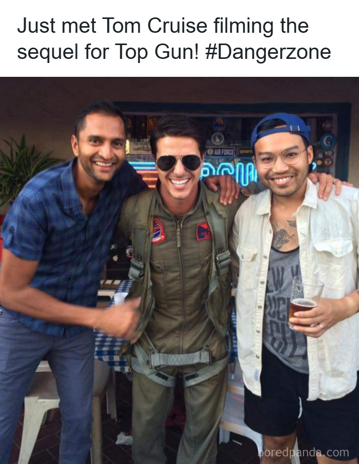 Three men posing for a photo with a Johnny Derp lookalike dressed as a Top Gun pilot smiling at an event.