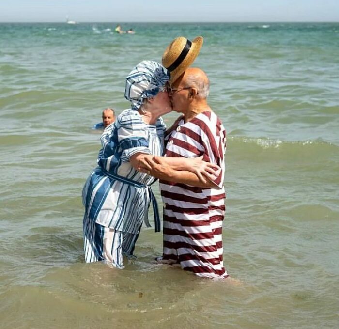Elderly couple in vintage swimwear sharing a tender moment in the sea, capturing beauty and wisdom of old age.