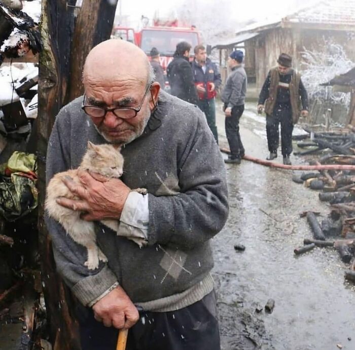 Elderly man holding a cat tightly in a snowy street scene, capturing the beauty and wisdom of old age.