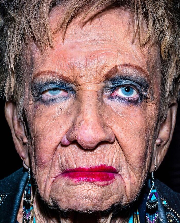 Close-up street photo of an elderly woman showcasing the beauty and wisdom of old age with expressive makeup.