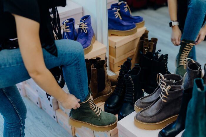 Person trying on green boots in a store surrounded by various boots, illustrating innocent people blamed by police concept.