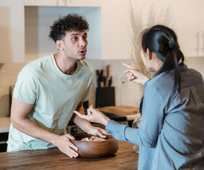 Young man and woman arguing in kitchen, discussing dream truck loan and owes inheritance issues intensely.