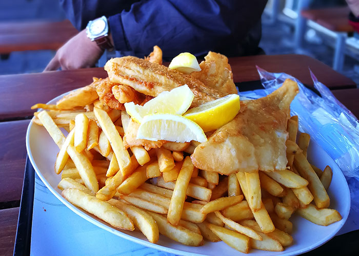 Plate of fried fish and French fries with lemon wedges, illustrating food industry workers dumbest customers stories.