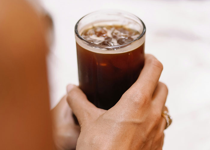 Person holding a glass of iced soda, illustrating dumbest customers food industry workers can’t forget about experiences.