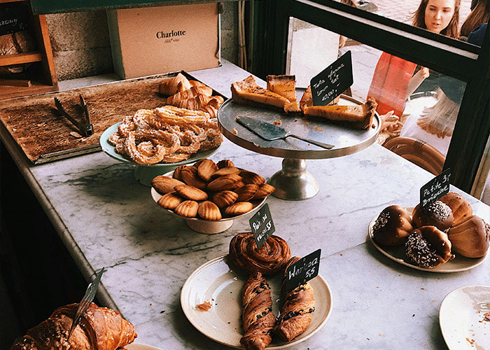 Display of assorted pastries on a marble counter in a bakery, highlighting food industry and customer service experiences.
