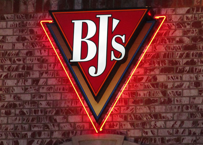 BJ’s restaurant sign with neon lighting on a brick wall, related to dumbest customers food industry workers remember.