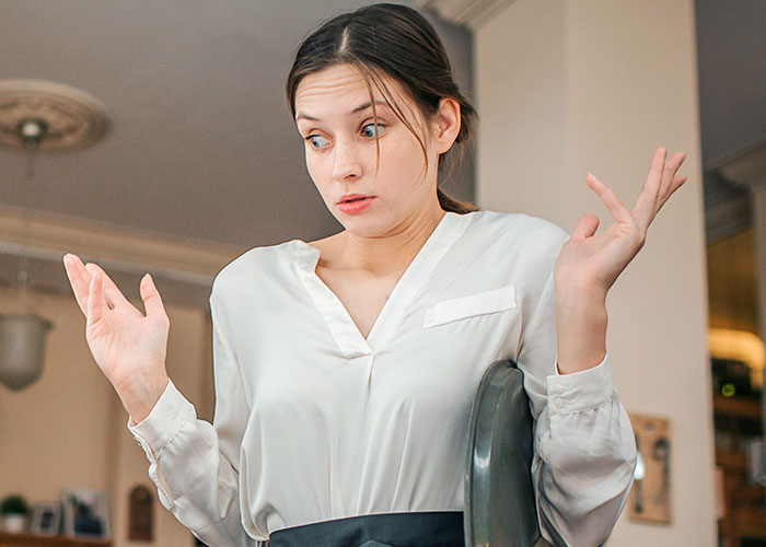 A confused food industry worker in a white shirt shrugging with raised hands, reacting to dumbest customers in the restaurant.