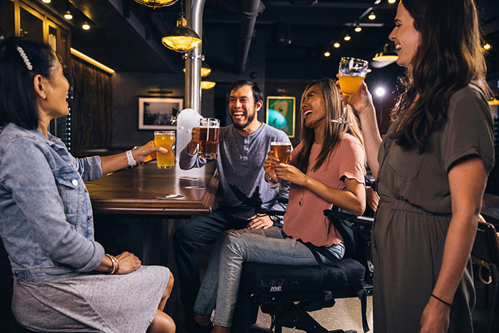 Group of friends toasting with drinks at a bar, illustrating unhinged ways company credit cards were used.