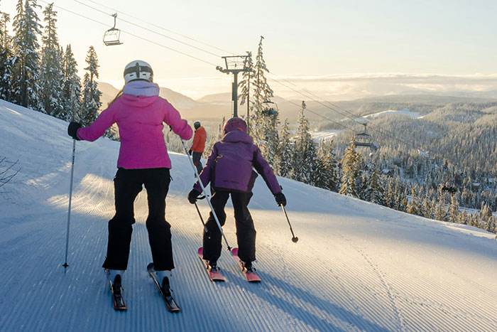 Two people skiing downhill on a snowy mountain with trees, illustrating unhinged ways company credit cards were used.