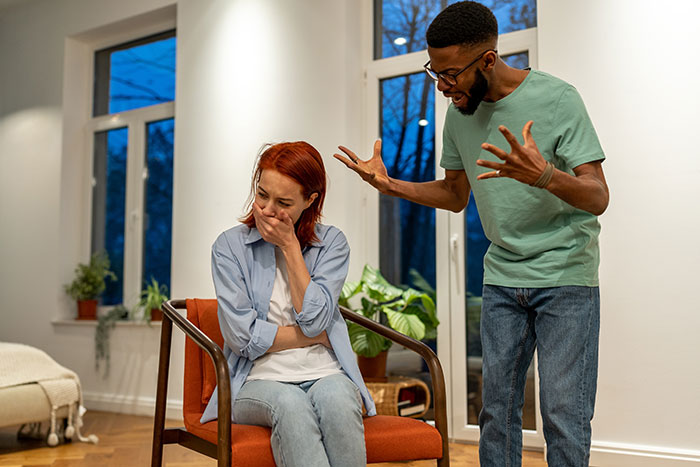 Couple arguing indoors as woman reveals solo trip plans, leading to tension and emotional upset in the relationship. Couple arguing indoors as woman reveals solo trip plans, leading to tension and emotional upset in the relationship.
