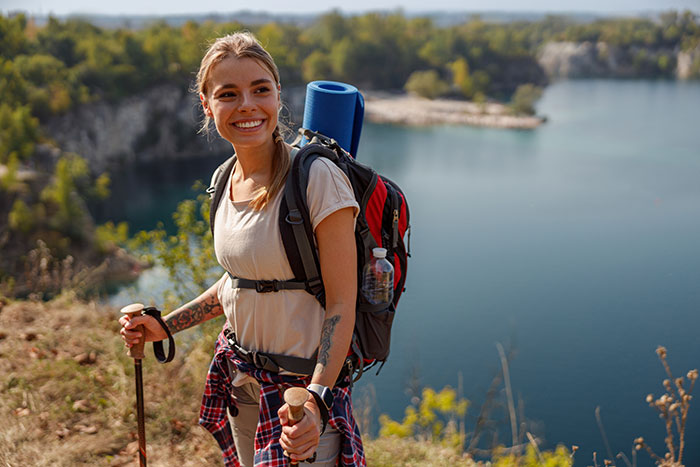 Woman solo trip planning with backpack and hiking poles near lake, enjoying outdoor adventure and nature views. Woman solo trip planning with backpack and hiking poles near lake, enjoying outdoor adventure and nature views.