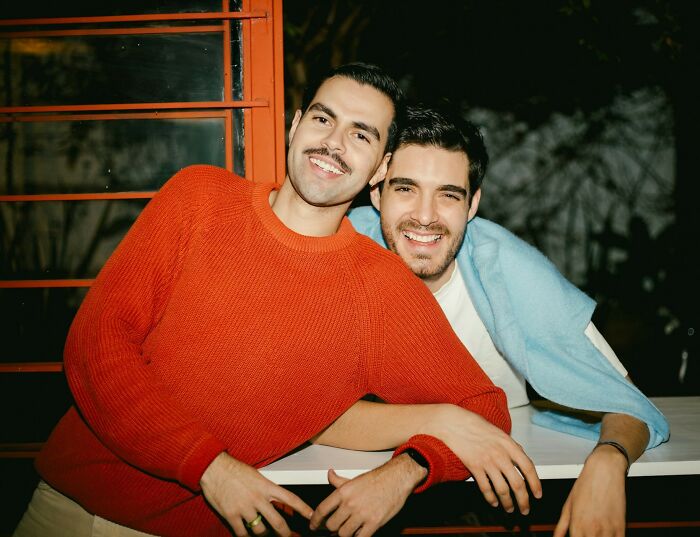 Two men smiling and leaning on a table, representing servers overhearing crazy stories in a casual setting.