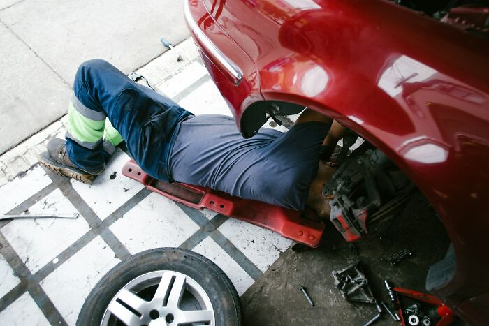 Mechanic working under a red car in a garage, illustrating patients who defied every medical odd according to doctors.