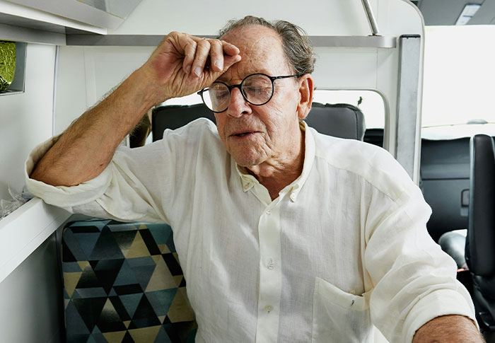 Elderly man wearing glasses in a white shirt looking concerned, possibly confronting a couple during a walk.