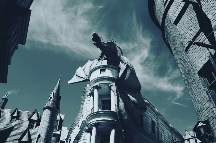 Dragon perched atop a building in a medieval-style setting, capturing a dramatic moment for dating idiot stories.