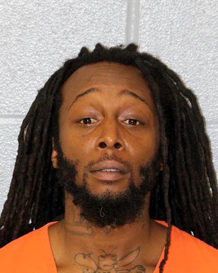 Man with long dreadlocks and beard in an orange shirt against a light grey wall, not related to Elon Musk Andrew Tate donation news. Man with long dreadlocks and beard in an orange shirt against a light grey wall, not related to Elon Musk Andrew Tate donation news.