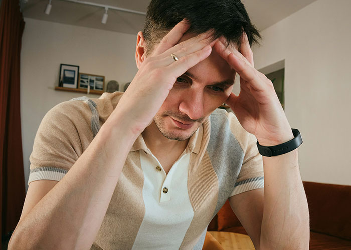 Man holding head in frustration indoors, illustrating facepalm-worthy doctor’s visits people wish they could forget.