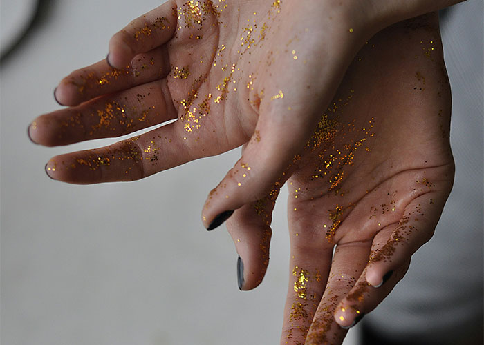 Close-up of hands covered in gold glitter, illustrating a quirky and messy moment during doctor’s appointments gone off the rails.