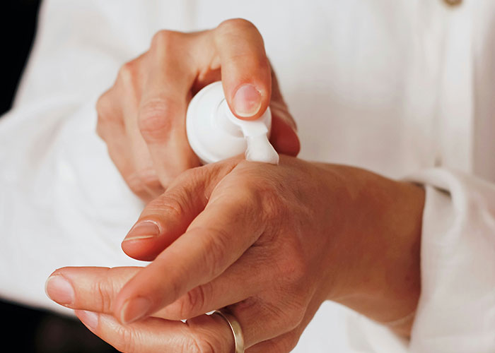 Person applying cream to hand, illustrating facepalm-worthy doctor visits people wish they could forget.