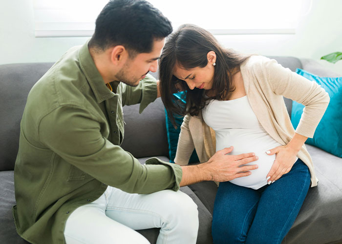 Couple at home experiencing a humorous and embarrassing moment during a doctor’s appointment discussion.