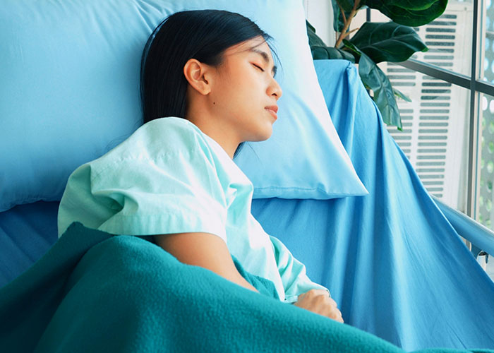 Patient resting in hospital bed with eyes closed, representing facepalm-worthy doctor’s visits and medical experiences.