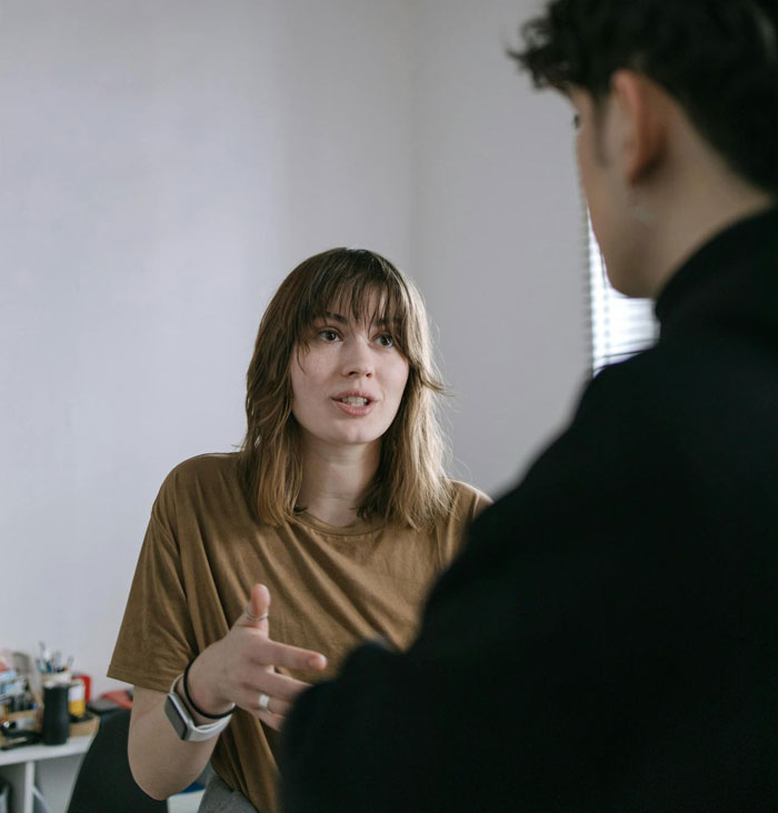 Young woman explaining adoption papers to another person in a casual indoor setting during a serious conversation