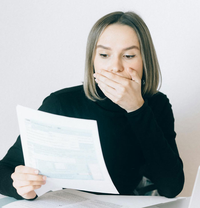 Woman in black sweater looking shocked while reading adoption papers at a desk, sister sends adoption papers mix-up.