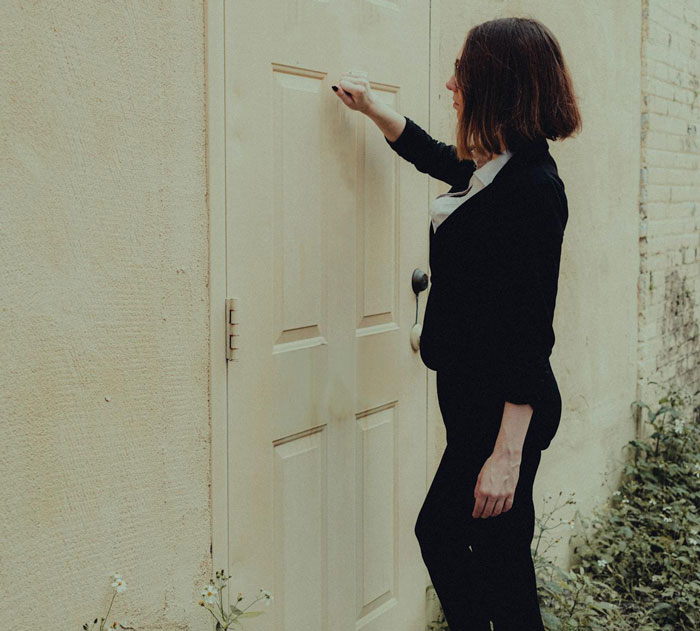 Woman in black outfit knocking on a door, linked to sister sends adoption papers babysitting misunderstanding story.