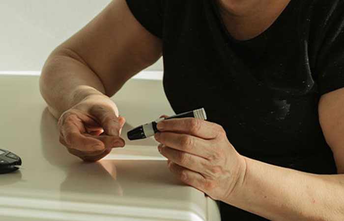 Healthcare worker using a blood glucose meter to check blood sugar levels in a clinical setting.