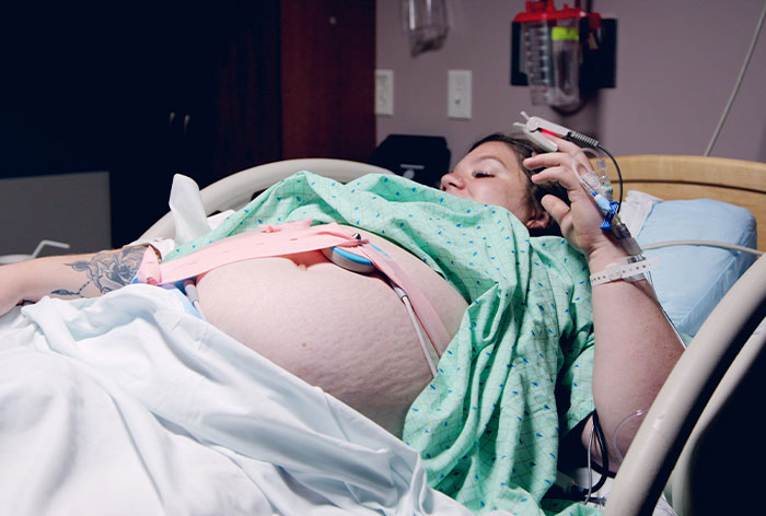 Pregnant woman in hospital bed receiving medical care, showing a healthcare workers critical intervention moment.