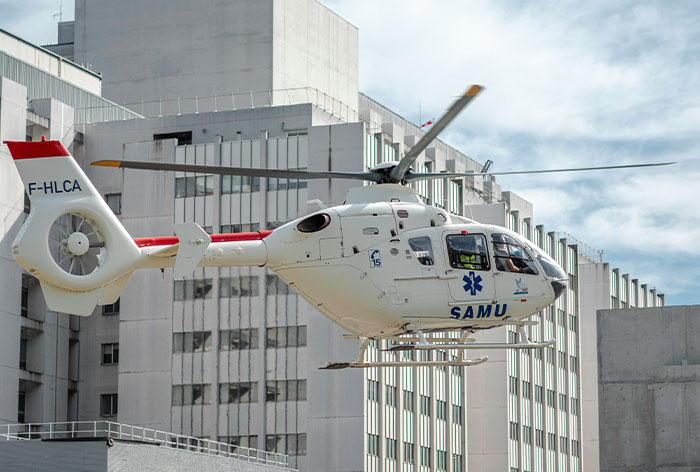 Emergency medical helicopter with healthcare workers flying near hospital buildings during a critical rescue mission.