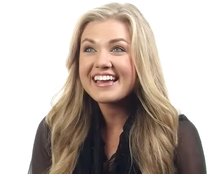 Smiling woman with long blonde hair and black top, related to Erika Kirk&rsquo;s past connection to Donald Trump and bikini photos.