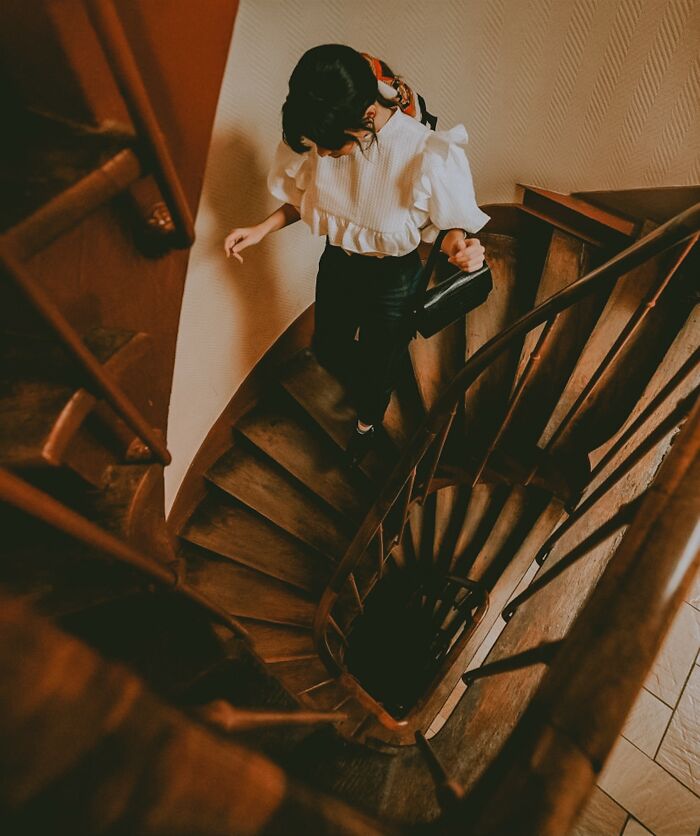 Woman walking down a wooden spiral staircase, capturing a moment of everyday things that humble fully grown adults.