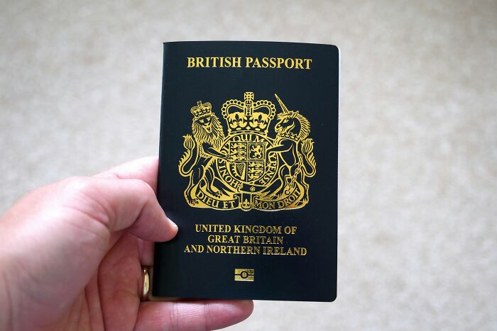 Hand holding a British passport symbolizing passengers eating passports and causing mayhem during flight. Hand holding a British passport symbolizing passengers eating passports and causing mayhem during flight.