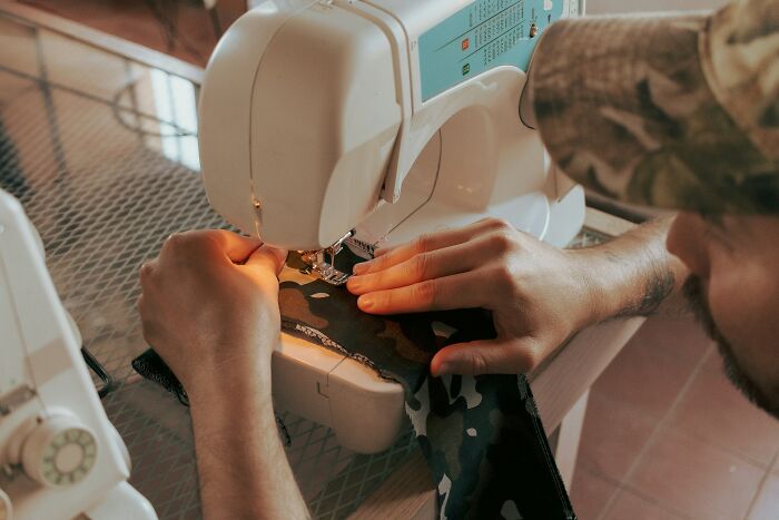 Person using a sewing machine on fabric, illustrating companies that sabotage products with poor design or quality issues.