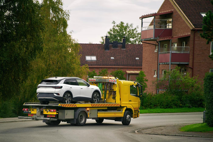 Tow truck carrying a white SUV on a residential street, illustrating a police warning over driveway disputes and entitlement.