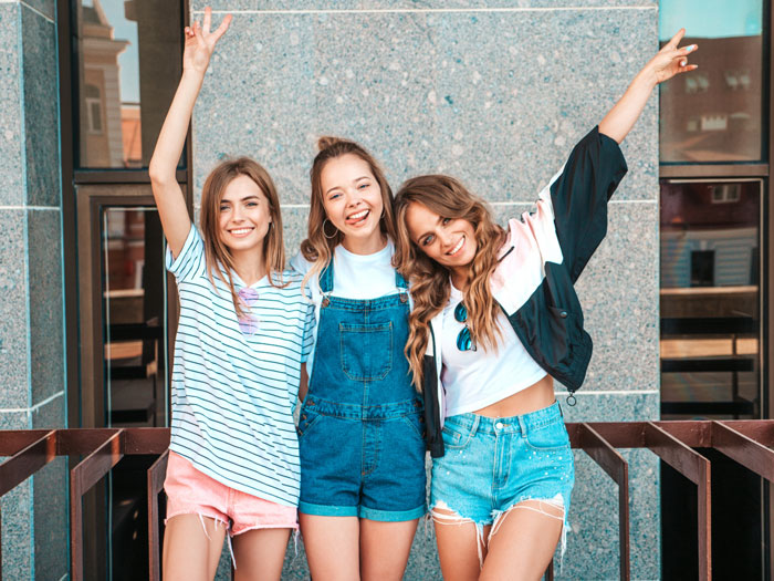 Three smiling young women posing outdoors, representing stepdaughter dating and love nest family conflict.